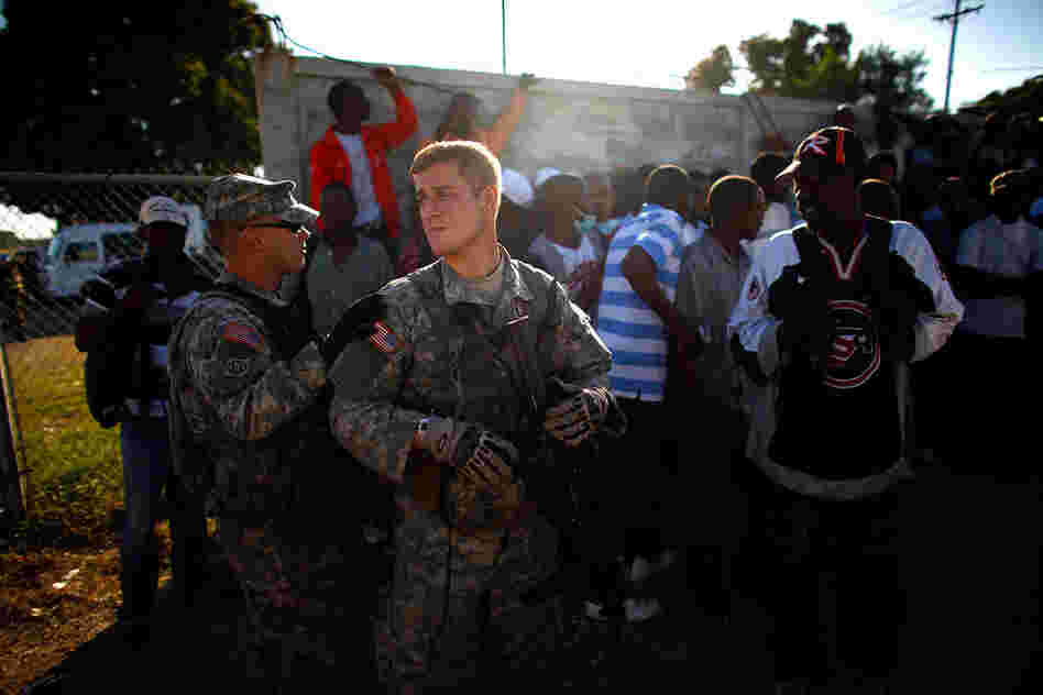 First Lt. Greg Bitner watches over Haitian men who have gathered at the airport in hopes of getting work.