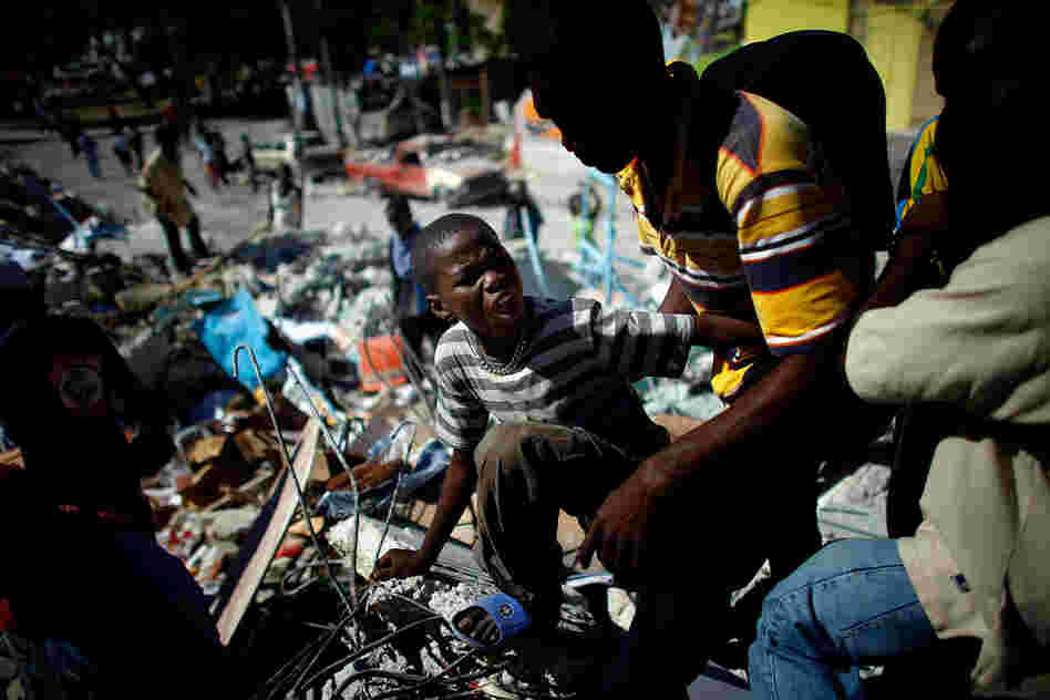 A boy tries to get a drink as looters scavenge the rubble of a supermarket Saturday in Port-au-Prince.