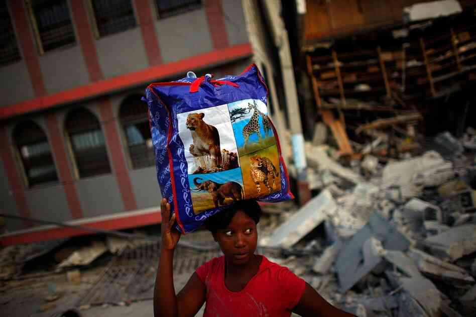 Across Port-au-Prince Haitians are scrambling to salvage what they can. A woman carries a bag of clothing recovered from her apartment.