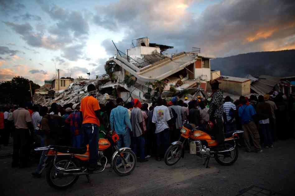 Haitians watch the L.A. rescue team's efforts at a collapsed building. Officials estimate at least 50,000 people were killed by the quake.