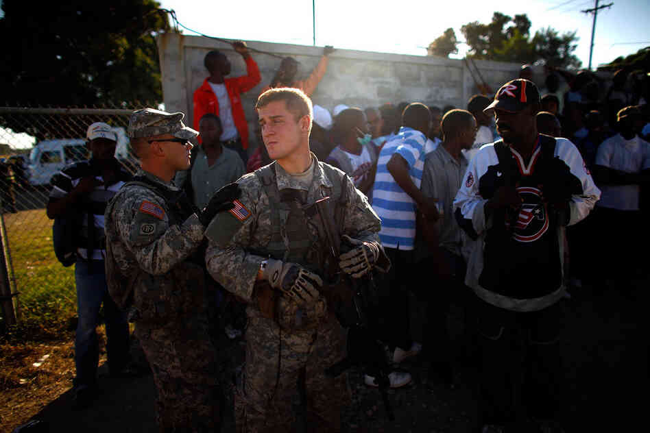 First Lt. Greg Bitner watches over Haitian men who have gathered at the airport in hopes of getting work.