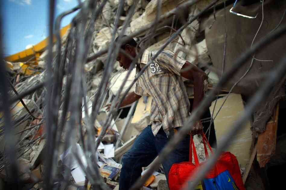 A Haitian man removes a bundle of goods from a collapsed store near Port-au-Prince.