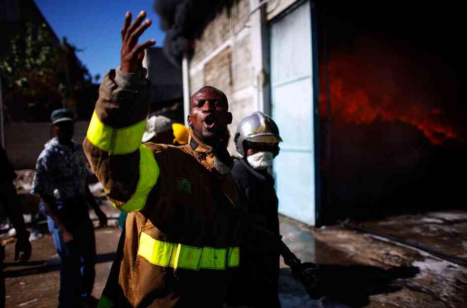Firefighters yell for help as they try to put out a fire at the Pasta Mamma noodle factory in Port-au-Prince on Monday.  