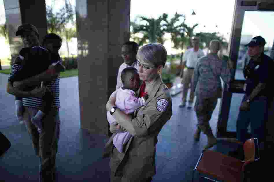 Melinda Pethel, a medical technician with the Georgia disaster assistance team, carries a baby into the American Embassy in Port-a-Prince on Monday. The baby arrived with a group from a Haitian orphanage.