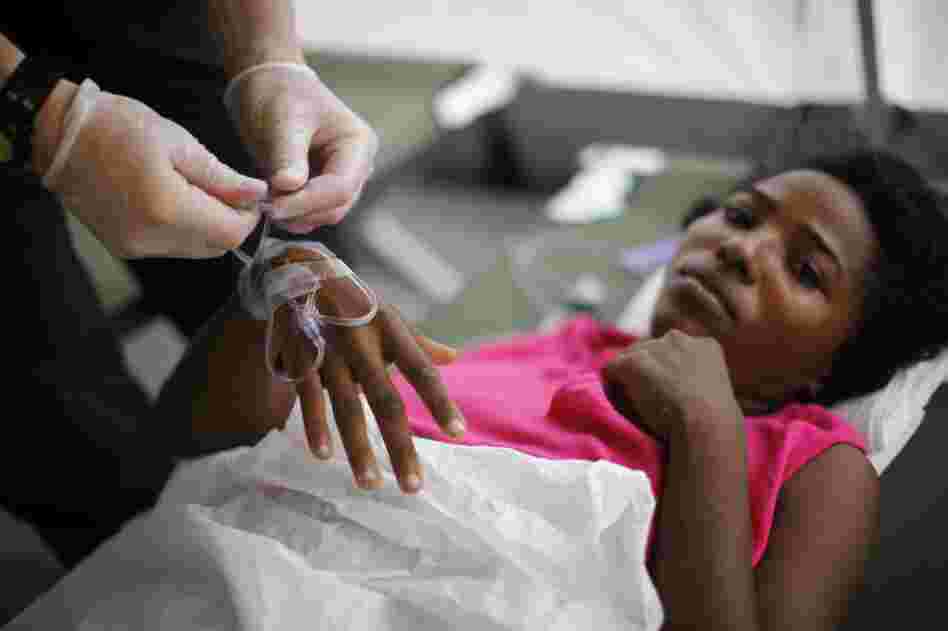 A nurse connects an intravenous tube to a patient inside the field hospital during its second day open.