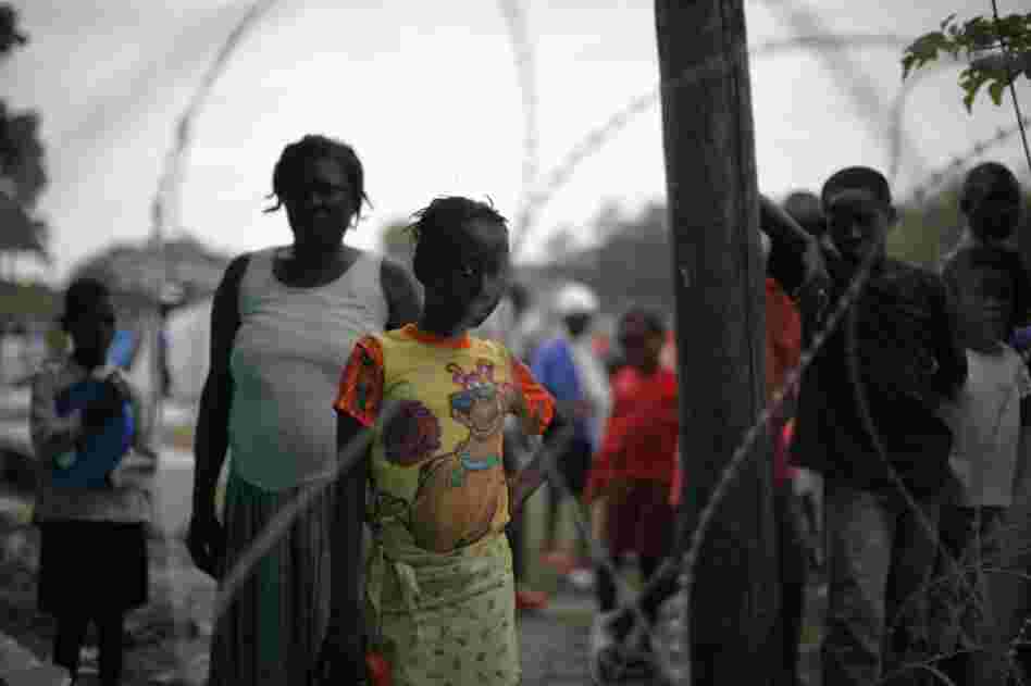 A girl peers though the wire separating the tent city from the field hospital.