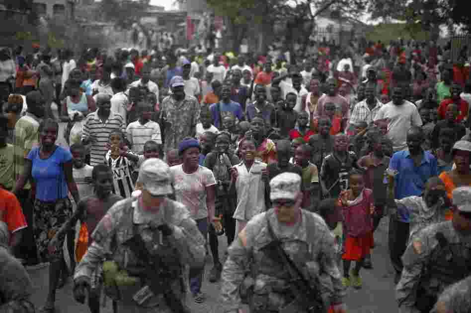 A growing group of Haitians follows the 82nd Airborne division convoy, in charge of protecting the field hospital, down the street.
