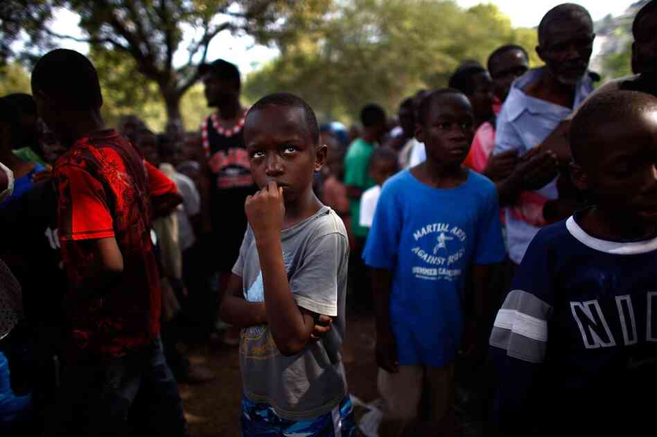 A boy waits for food supplied by the U.S. Army at a golf club above the capital.