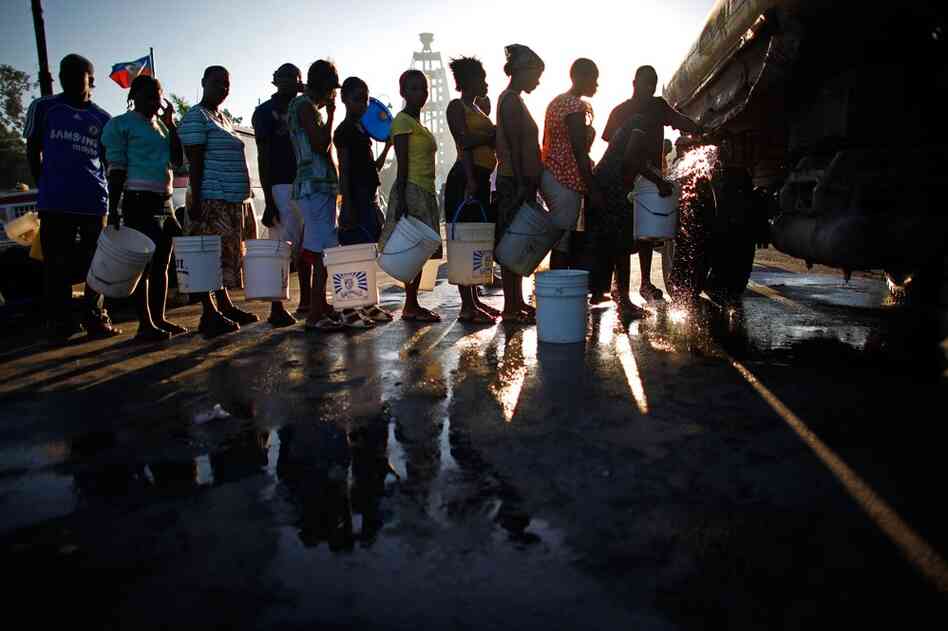 Women stand in a line for water in a park turned refugee camp across from the National Palace Thursday.