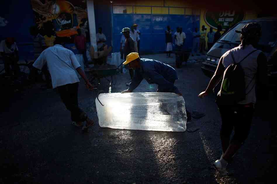 Men move blocks of ice from the only functioning ice plant in the city. Without power, it's the only way to keep food cool.  