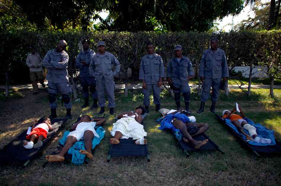 Haitian National Police stand over patients in front of the National Palace waiting to be evacuated Thursday.