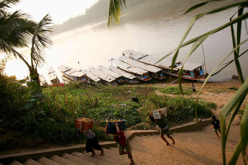 Workers unload produce from boats at a dock on the Mekong in Luang Prabang, Laos.