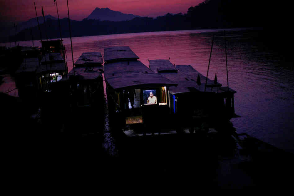 At sunset, a woman works on her boat on the Mekong in Luang Prabang.