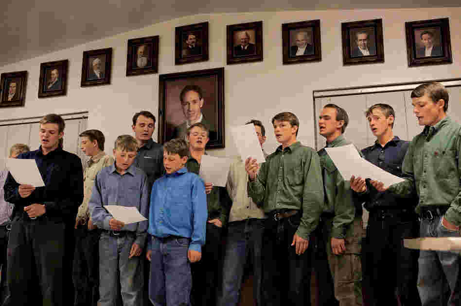 "Singing is a nice way to wind down the day, but it's hard to manage during harvest time," says Aaron Jessop Jr. He stands beneath a large picture of Warren Jeffs, the former president of the FLDS, who is serving a prison sentence for arranging marriages with underage girls.