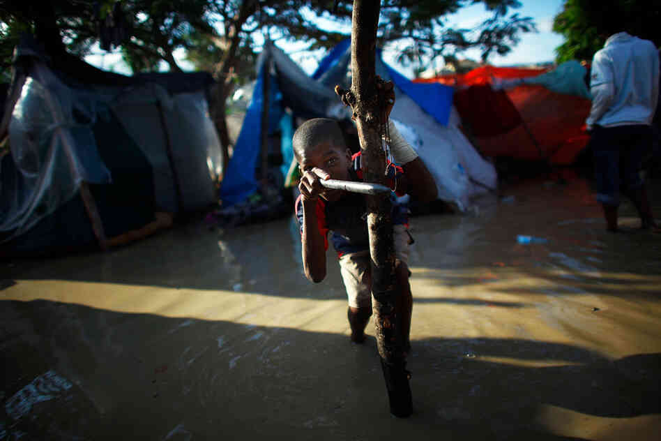A young boy plays in contaminated water outside a flooded tent in the Mais Gate tent city after heavy rains flooded the area in the middle of the night on Thursday. Quake survivors tried to stay dry and dig tents out of the mud, but they are already having to relocate to new camps.