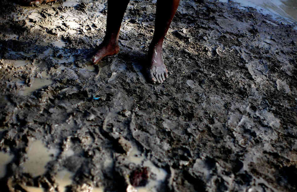 Ten-year-old Alex Mertulus stands in the mud in the Mais Gate tent city. He and his mother, Margarette Brutus, are fighting a losing battle as they try to find durable, dry housing.