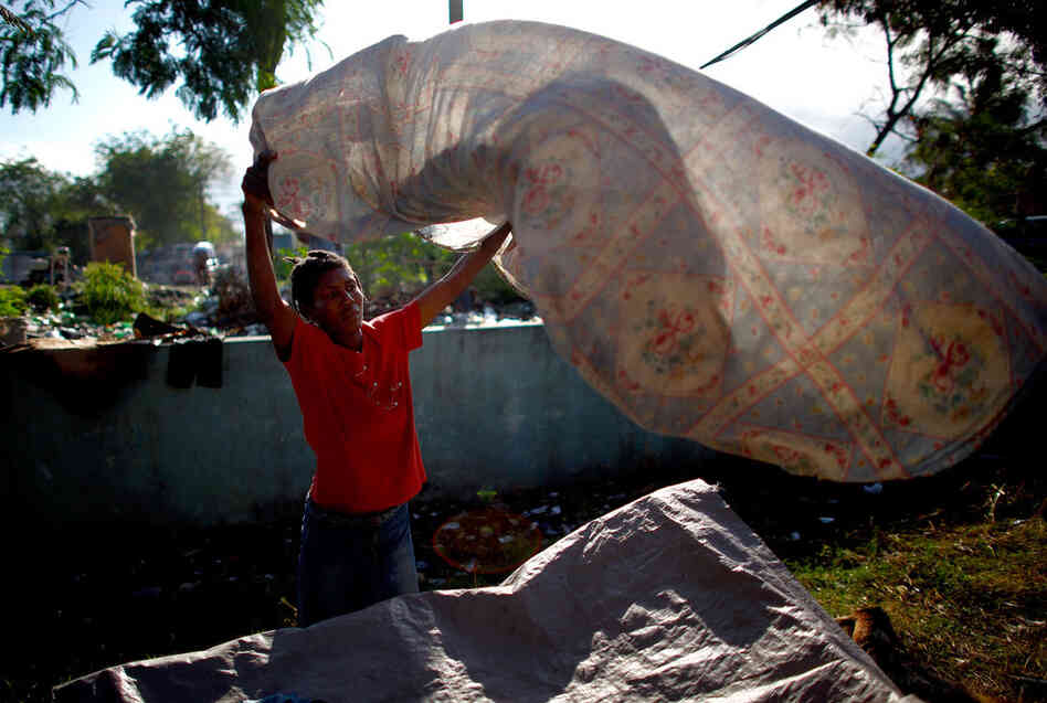 Margarette Brutus, 50, tries to clean a bedsheet soiled by the muddy waters that flooded her tent after heavy rains. Since the earthquake, her family has been divided, as she found more stable housing for her older children in different camps.