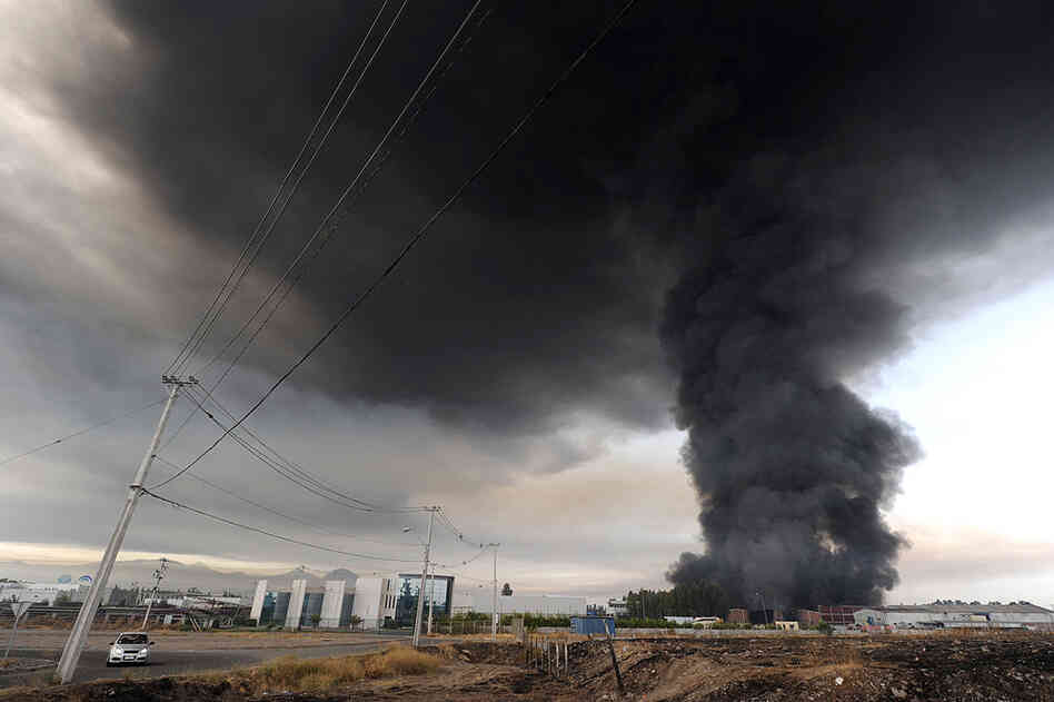 Smoke from a burning building fills the sky on the outskirts of Santiago. 