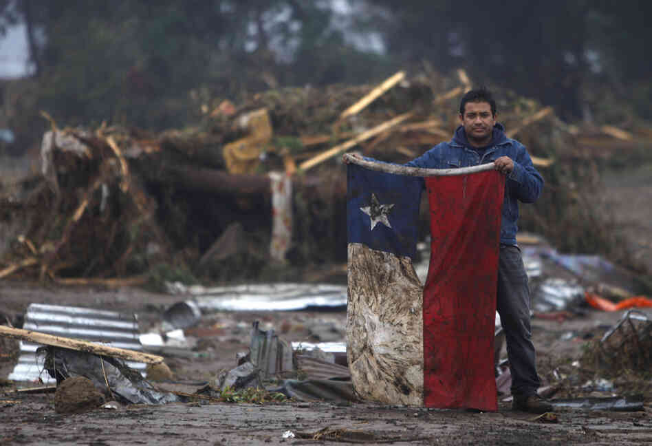 A man holds a torn and soiled Chilean flag on Sunday in a flooded area of Pelluhue, about 200 miles southwest of Santiago. 