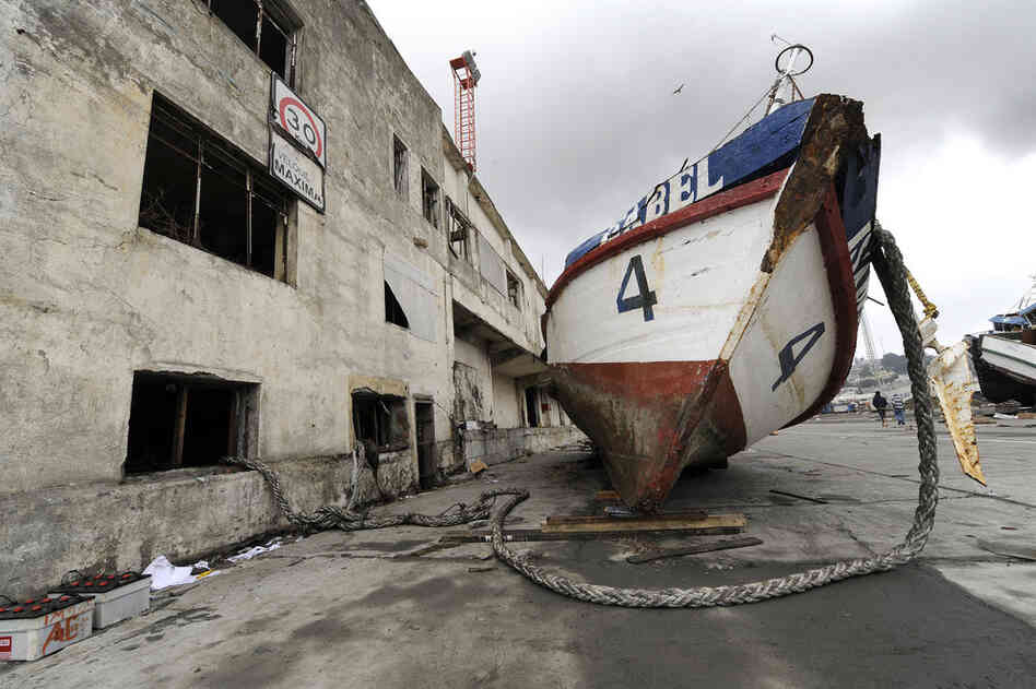 A boat rests next to a building Monday after it was washed ashore by the tsunami in Talcahuano. 