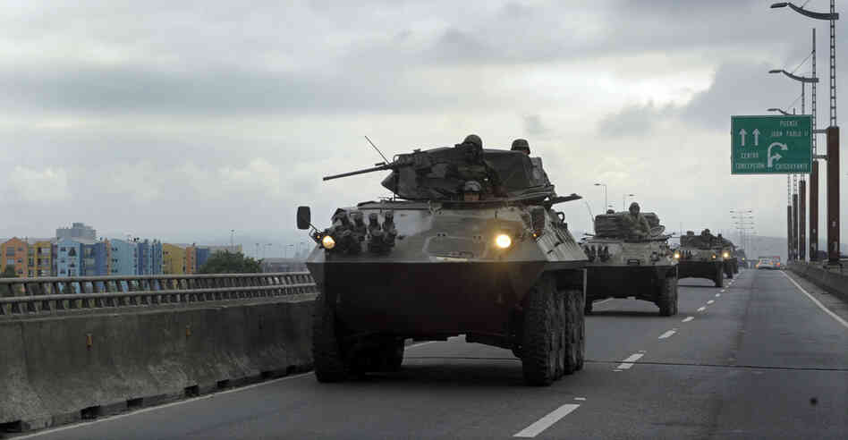 Chilean army armored personnel carriers drive along a bridge Tuesday in Concepcion, the country's second-largest city. Bachelet said Chile has dispatched 14,000 to devestated areas. 