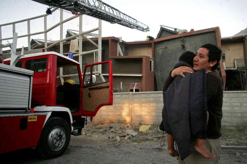 A man holds a child outside a quake-damaged building in Concepcion early on Saturday. 