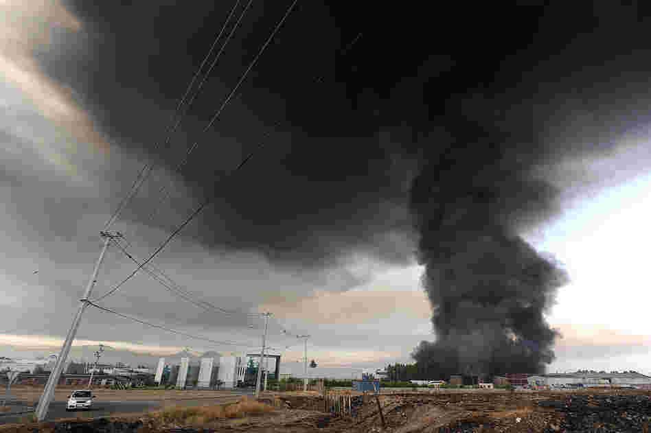Smoke from a burning building fills the sky on the outskirts of Santiago. 