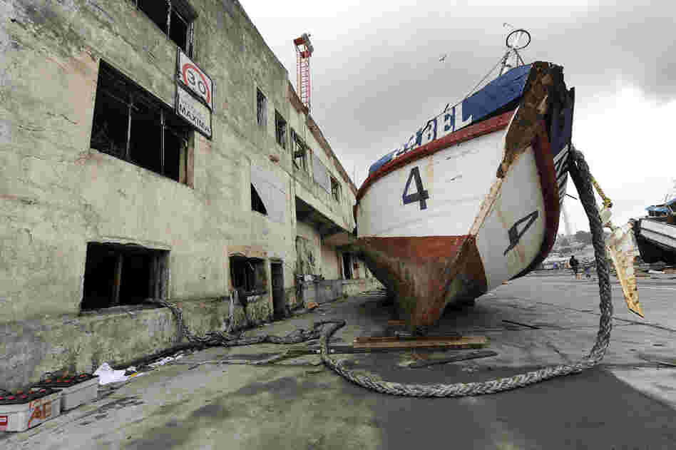 A boat rests next to a building Monday after it was washed ashore by the tsunami in Talcahuano. 