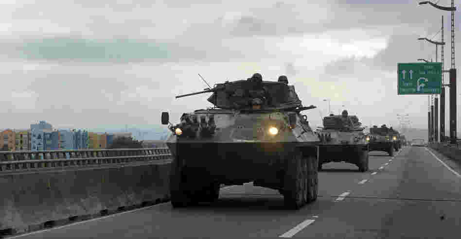Chilean army armored personnel carriers drive along a bridge Tuesday in Concepcion, the country's second-largest city. Bachelet said Chile has dispatched 14,000 to devestated areas. 