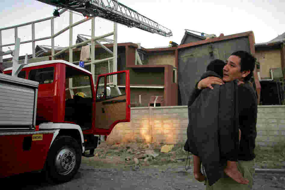 A man holds a child outside a quake-damaged building in Concepcion early on Saturday. 