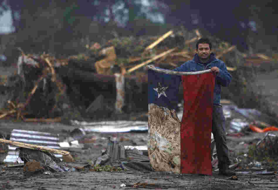 A man holds a torn and soiled Chilean flag on Sunday in a flooded area of Pelluhue, about 200 miles southwest of Santiago. 