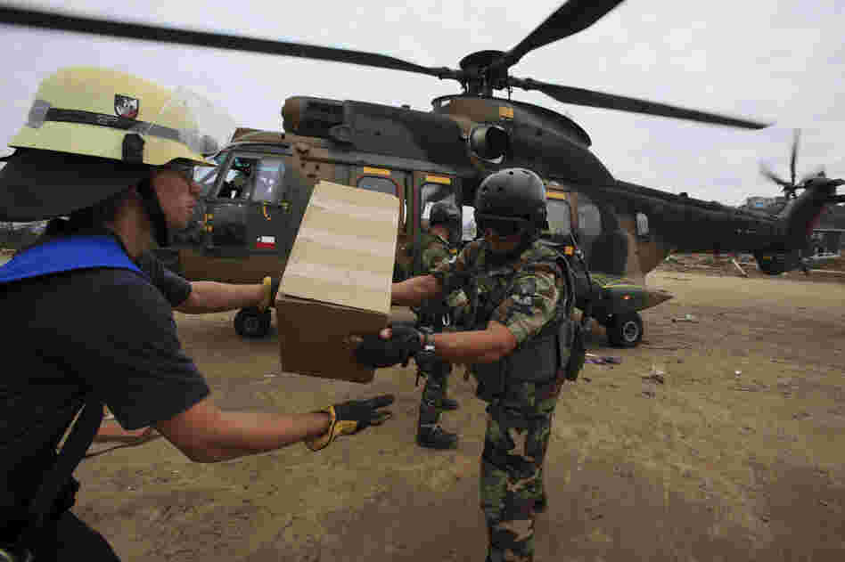 Chilean troops and firefighters unload relief supplies Wednesday from a military helicopter in the coastal town of Dichato, which was heavily damaged by tsunami waves produced by Saturday's 8.8-magnitude earthquake.