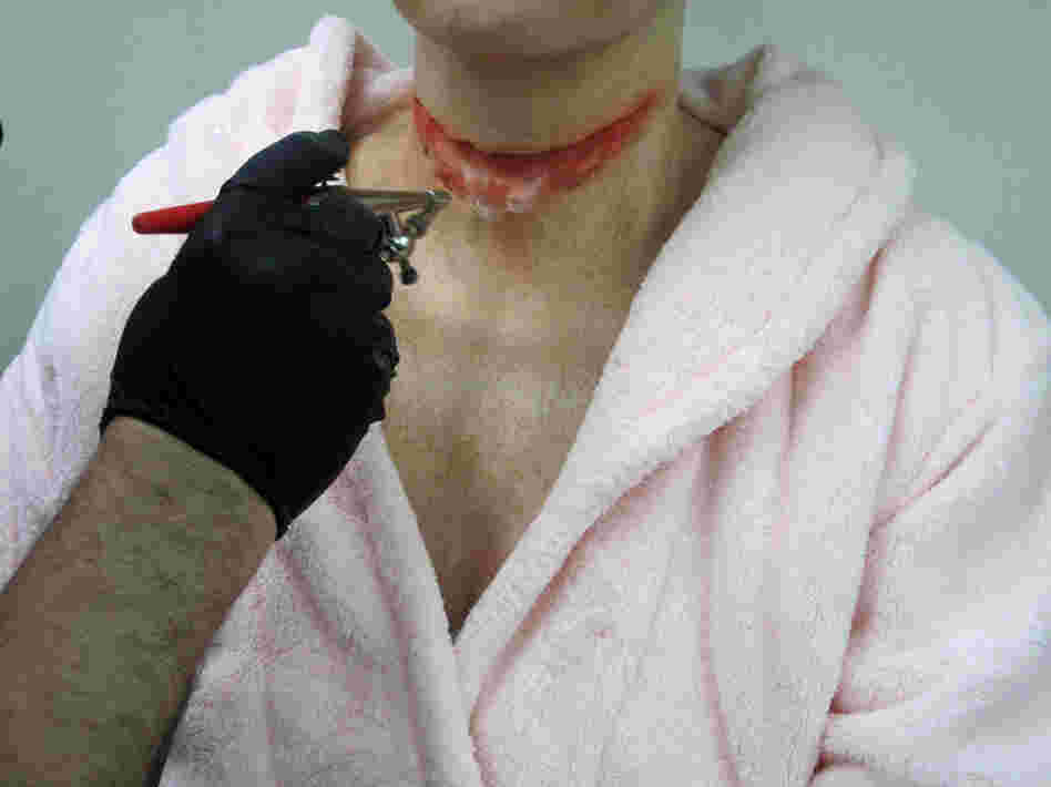 Constantine sprays red coloring — "the blood" — onto the "wound."