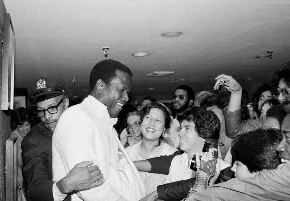 A security guard shields actor Sidney Poitier from a mob of fans, June 11, 1980, New York City.