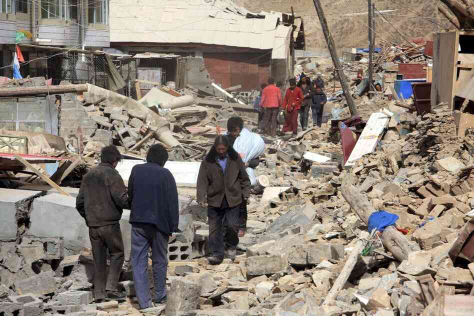 People walk on the ruins of crumbled buildings in Yushu. The earthquakes also triggered landslides, the official Xinhua news agency reported. 