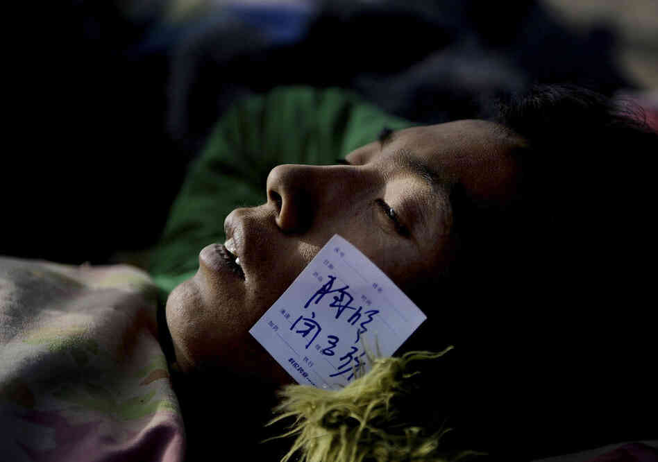 An injured survivor with a paramedic tag waits for medical treatment at a gymnasium following the earthquake in Yushu county in western China. 