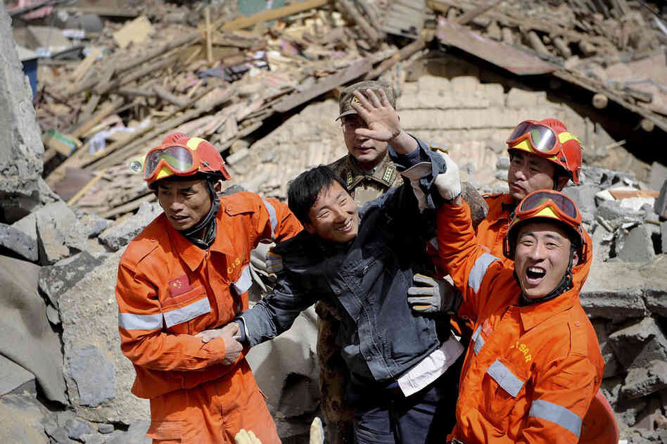 A survivor waves after being rescued from rubble of a collapsed building. The region sits at about 13,000 feet, and many rescue workers were suffering from altitude sickness. 