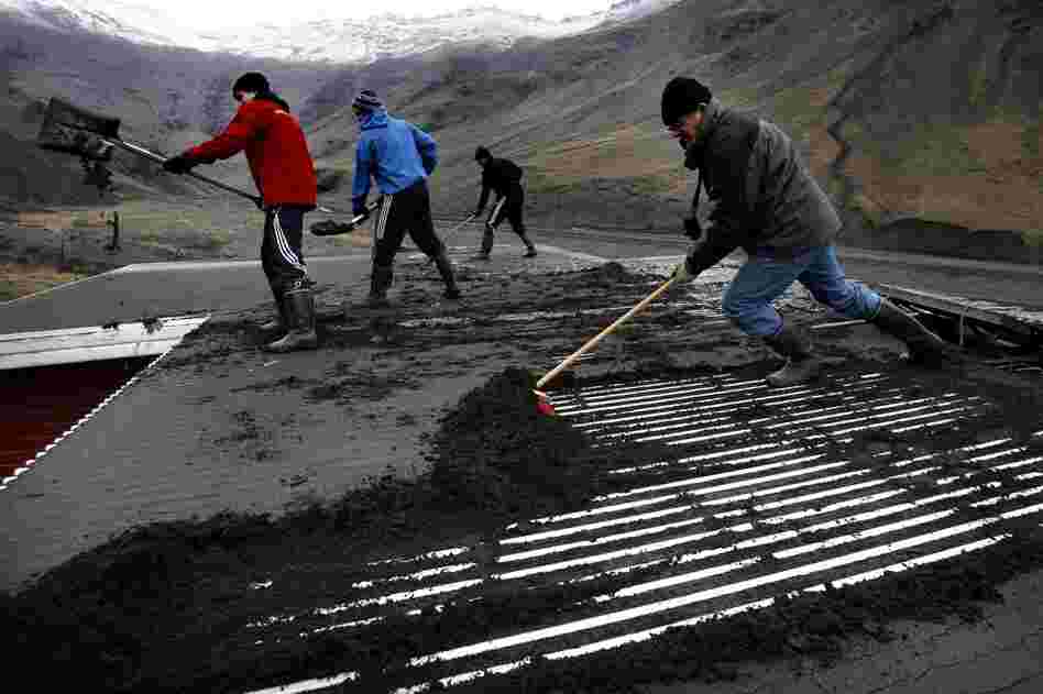 Men labor to remove volcanic ash from the roof of a house, in Seljavellir, Iceland,  April 18. 