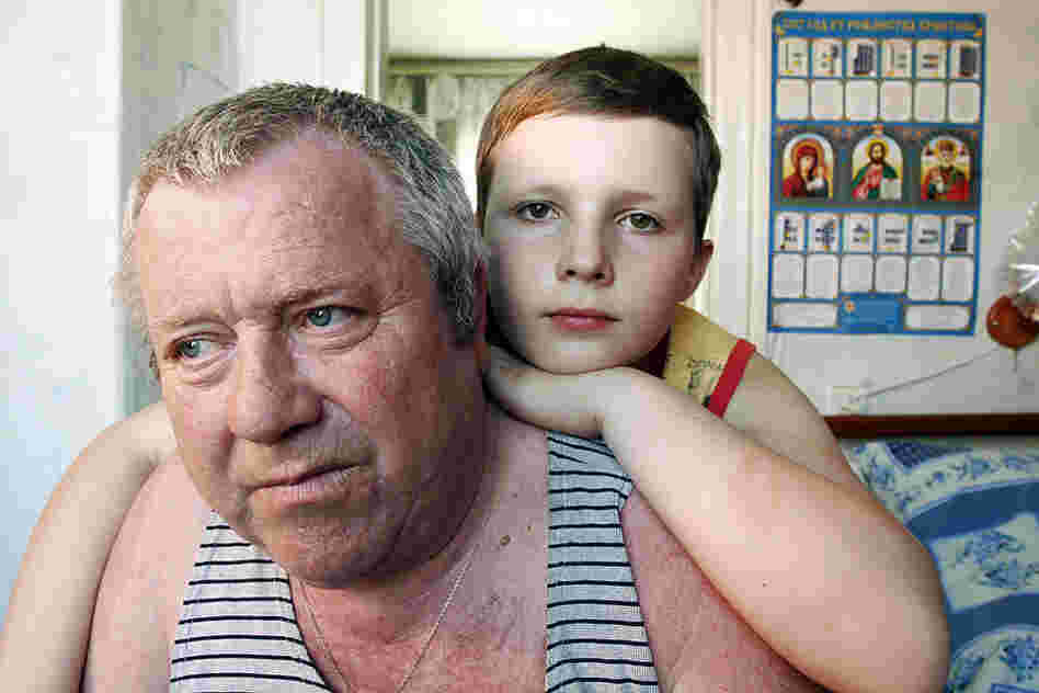 "In 1986, Leonid Budkovskiy (here with his grandson, Slava), then a mailman in Ivankiv, was reassigned to deliver top-secret mail to the military headquarters set up in Chernobyl. He continued for four years ... His legs slowly stopped working and by 1996 he was confined to a wheelchair."