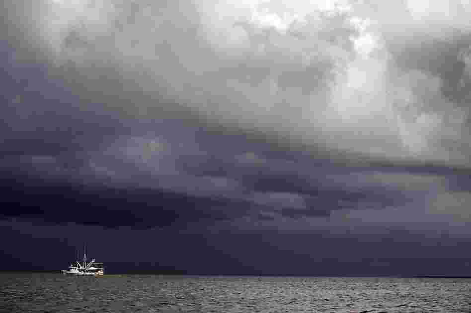 A boat uses a boom and absorbent material to soak up oil in Cat Bay, near Grand Isle, La., on June 28. A tropical storm is expected to hit the Gulf and impede cleanup efforts. 