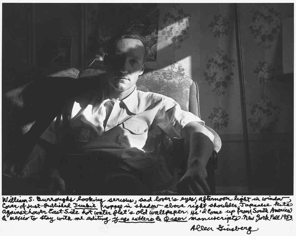"William S. Burroughs looking serious, sad lover's eyes, afternoon light in window, cover of just-published Junkie propped in shadow above right shoulder, Japanese kite against Lower East Side hot water flat's old wallpaper. ... New York Fall 1953."