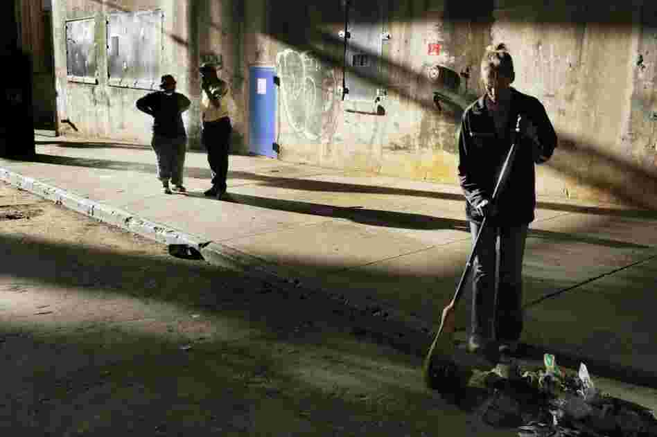 Snow White sweeps litter on the dead-end street known as "The Bat Cave." The street is swept daily to keep down rats and flies. Country and Tasha talk in the background.