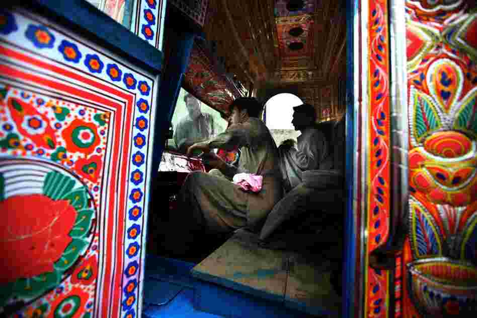 Truck art contractor Muhammad Zaman, 43, far left, washes the windshield of a newly painted truck as his workers clean its interior. Contractors coordinate all the decorating work — they line up the various craftsmen and the specific artist to paint the detail work on the trucks.