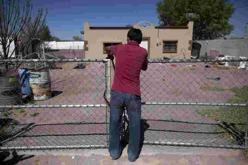 A 14-year-old boy locks the front gate of his house while fleeing El Porvenir with his family.