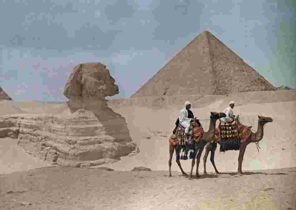 Men on camelback stride past the Great Pyramid and the Sphinx before it was excavated, Giza, Egypt, 1925 