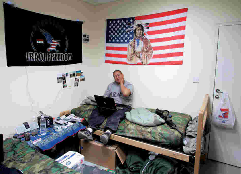 William Estevan, of the Navajo tribe, keeps in touch with friends and family from his barracks room at Camp Cropper, Iraq. Photos of relatives and views of his home near Acoma, N.M., plaster the wall.