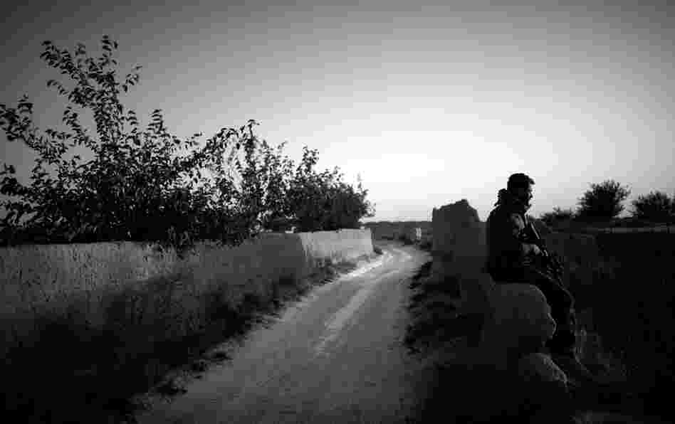An Afghan commando sits on a mud wall while securing a road during a patrol in the village of Ezabad. Perhaps an auspicious beginning for cooperation between Americans and Afghans, the road ahead looks long and arduous.