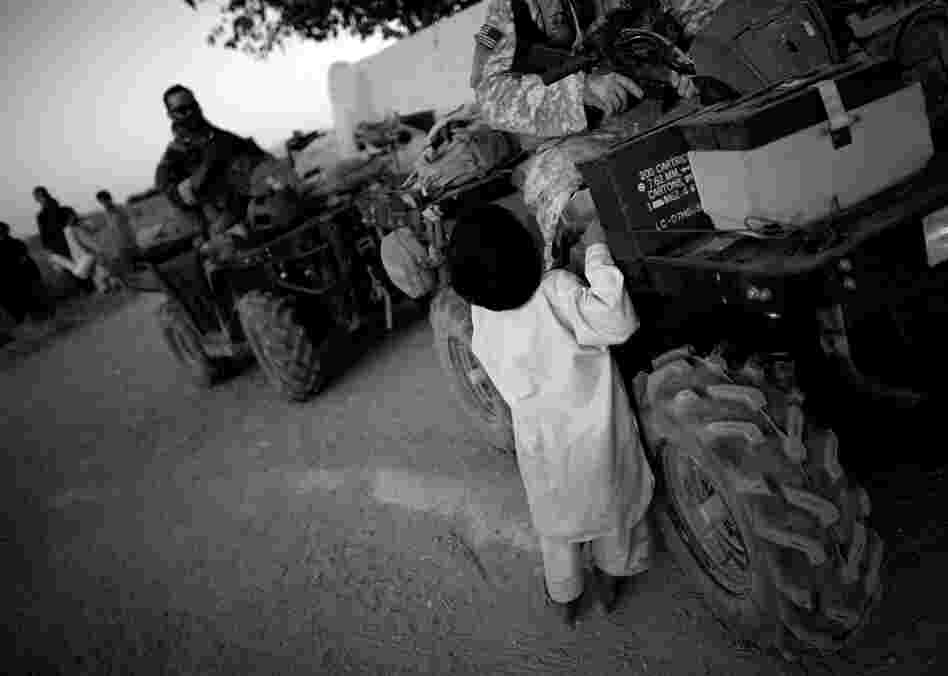 A child approaches Green Berets on patrol in Ezabad. Special Forces use ATVs (or all-terrain vehicles) for better mobility across rough terrain and narrow village roads.