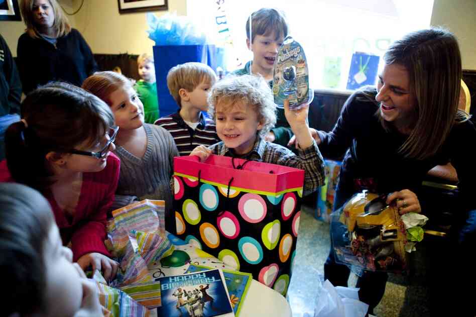 Brianne Zimmerman helps her son, Noah Garland, open presents during his birthday party at Shrewsbury Lanes in St. Louis. She and her husband, Nathan Garland, represent a growing trend of couples who opt to have children without first being married. 