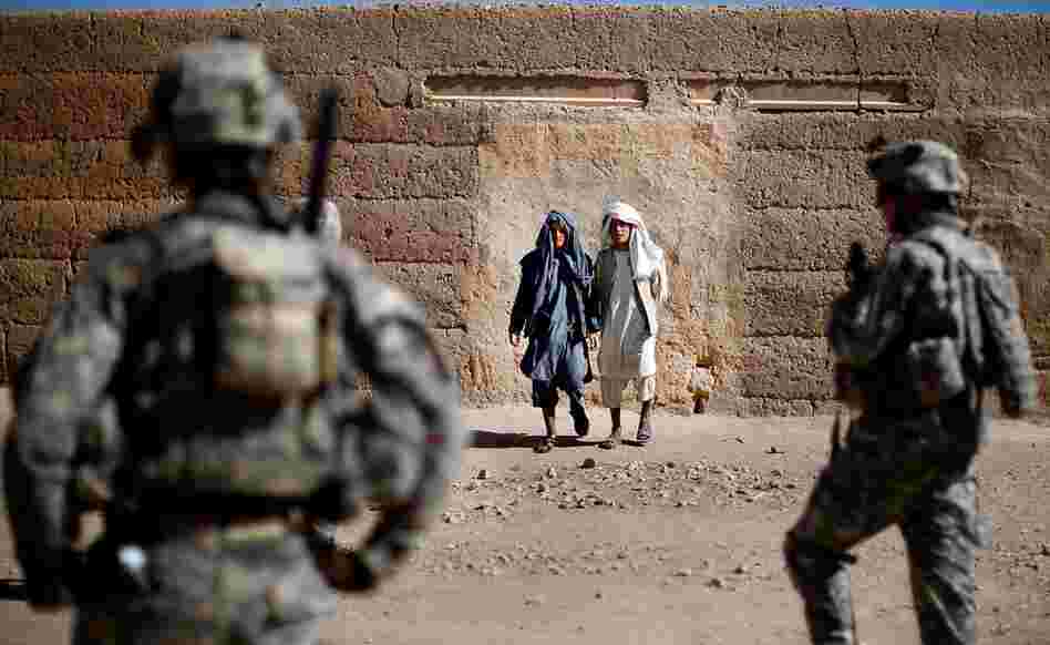 Villagers in Sangeray watch soldiers from Alpha Company during the patrol. The dense urban environment makes it easy for Taliban insurgents to throw grenades at the soldiers and disappear into the surroundings.
